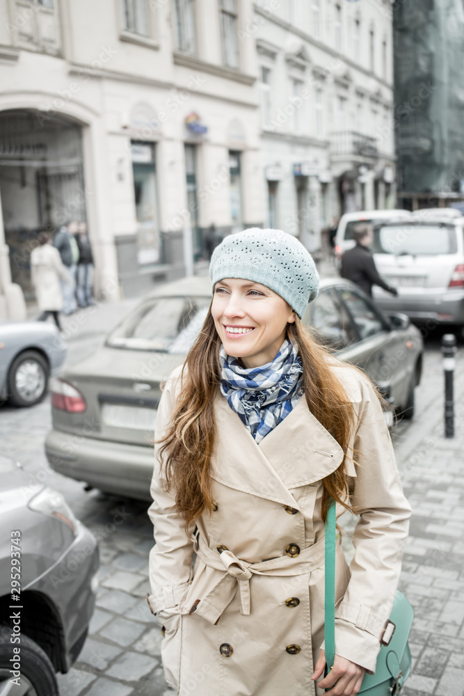 Happy young adult woman smiling outdoors and walking on city street wearing autumn clothes and scarf Happy young adult woman smiling outdoors and walking on city street wearing autumn clothes and scarf