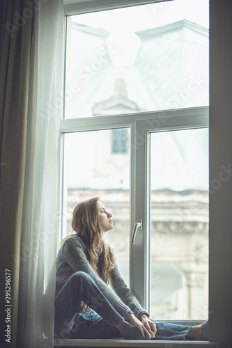 Beautiful young woman sitting by the window