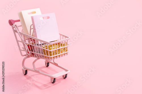 Murais de parede Annual sale shopping season concept - mini pink shop cart trolley full of paper