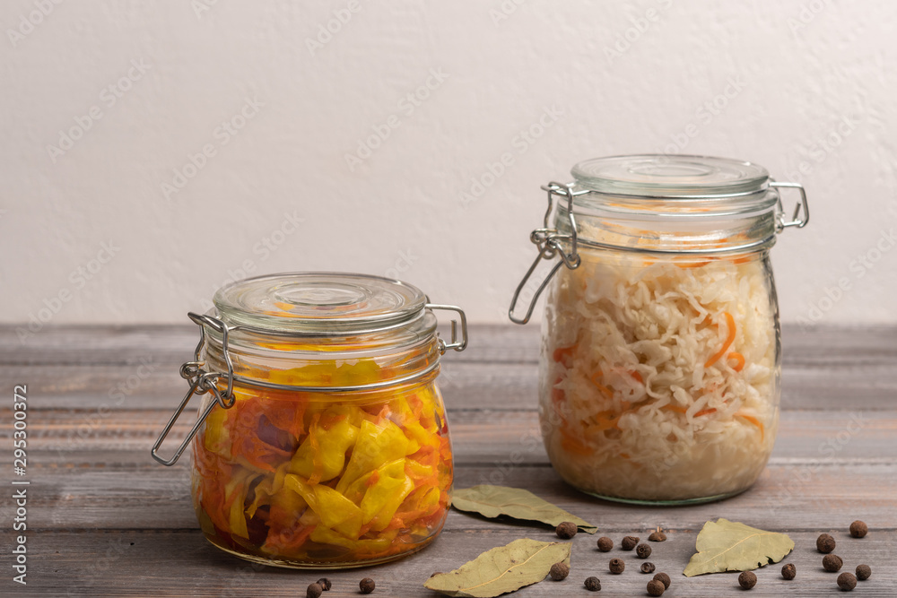 Homemade canned cabbage in jars with pepper and bay leaves on a wooden table. Rustic style Homemade canned cabbage in jars with pepper and bay leaves on a wooden table. Rustic style