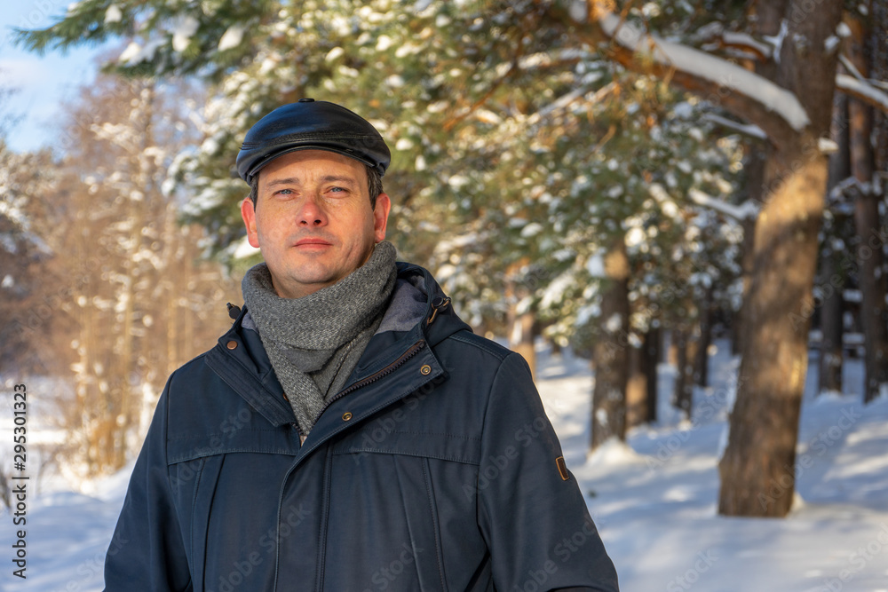 Portrait of handsome middle-aged man against beautiful winter landscape. Man walking in snowy forest in sunny frosty day. Human and nature, winter holidays, weekend at countryside concept