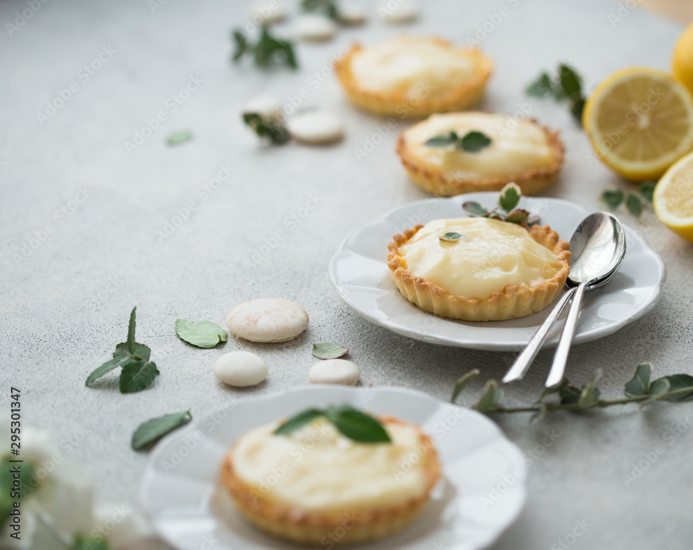 Fototapeta premium Lemon curd tart served with green leaves and lemon. Tartalets, lemon curd tarts