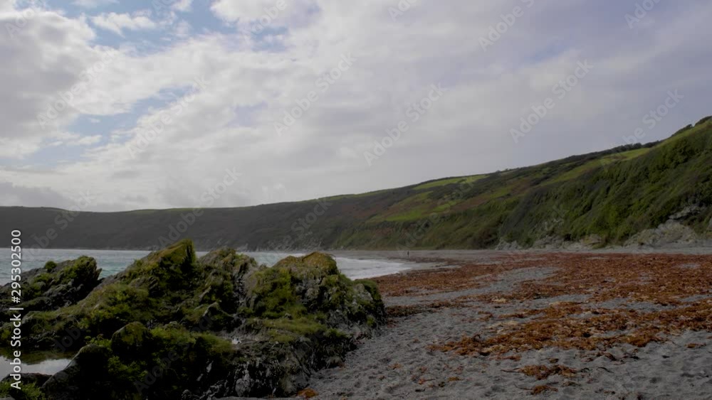 4K video panning from beach over rocks and sea with clouds