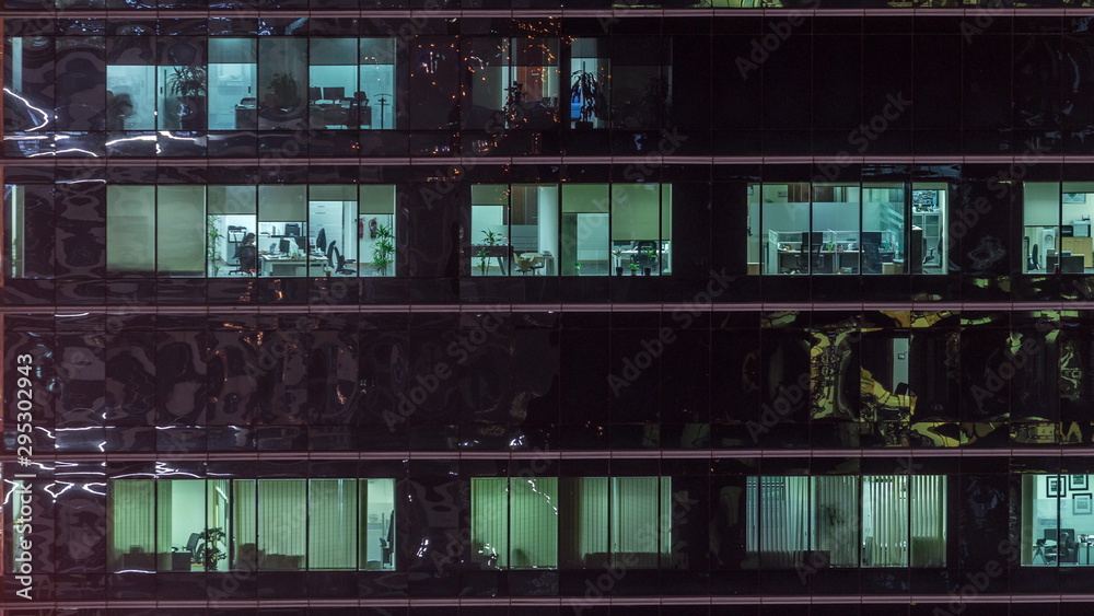 Office skyscraper exterior during late evening with interior lights on and people working inside night timelapse Office skyscraper exterior during late evening with interior lights on and people working inside night timelapse