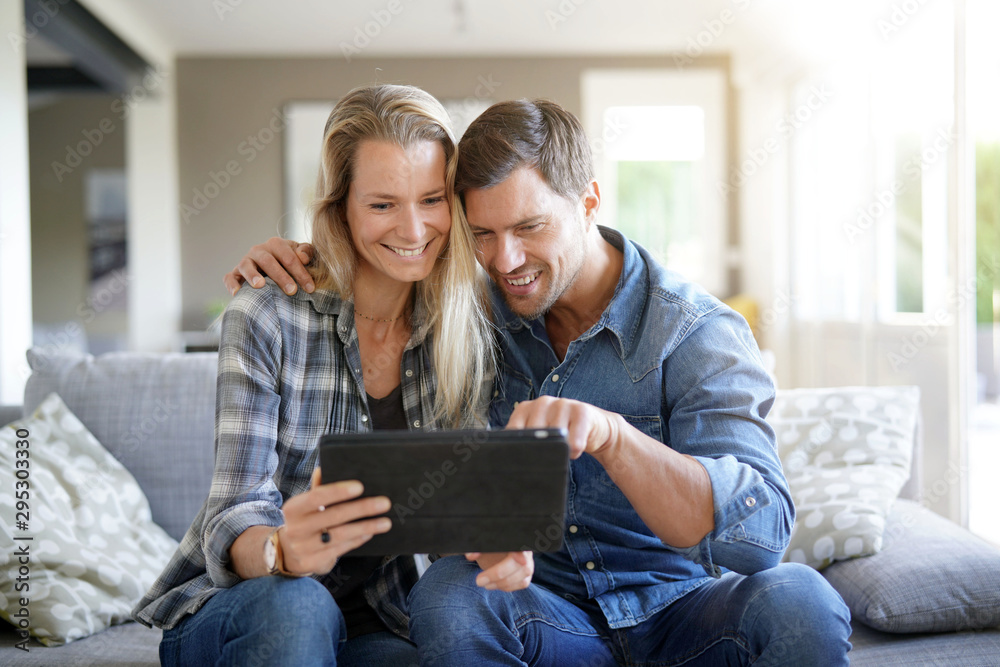 Smiling couple at home using digital tablet