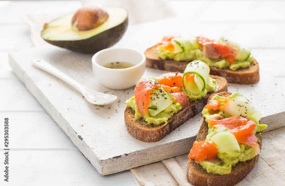 sandwich with avocado and salmon on a light background, green onions and gluten-free grain bread, radishes and cucumbers. concept diet food, copy space, sandwich take away, healthy fast food sandwich with avocado and salmon on a light background, green onions and gluten-free grain bread, radishes and cucumbers. concept diet food, copy space, sandwich take away, healthy fast food