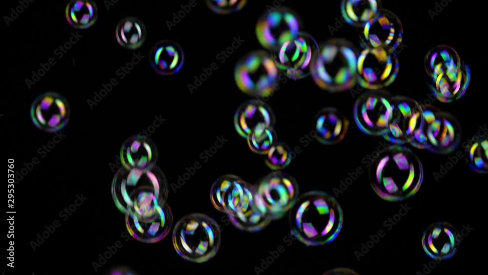 Colorful soap bubbles fly across black background. 