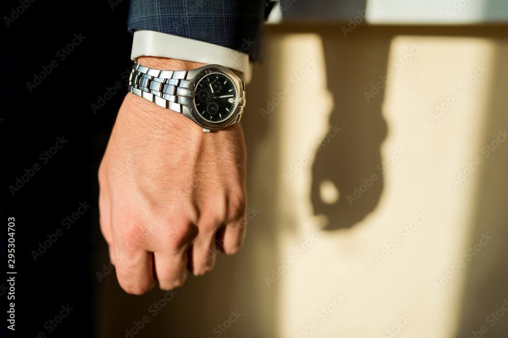 The man in the white shirt and dark suit with brand luxury limited version watches. Shade background.