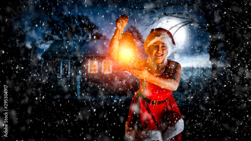 Slim young woman with lamp and christmas night 