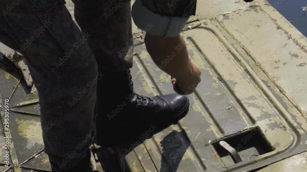 Military soldier closes the hatch cover on a pontoon bridge