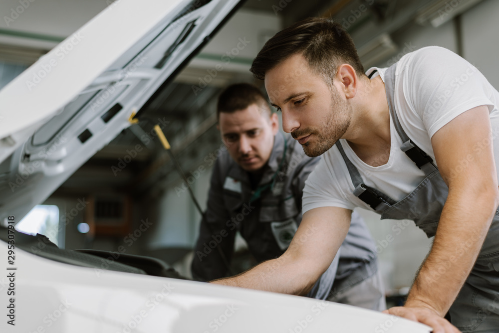 Auto mechanics working on car engine in a workshop Auto mechanics working on car engine in a workshop