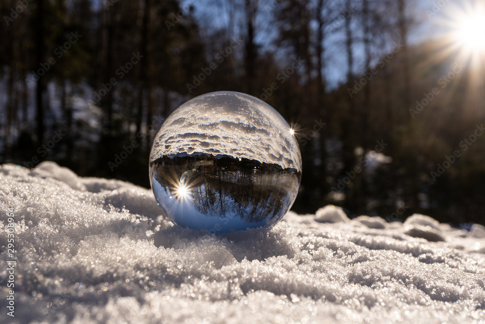 lens ball during winter in austria europa, crystal ball in the snow with an amazing sunset in the background