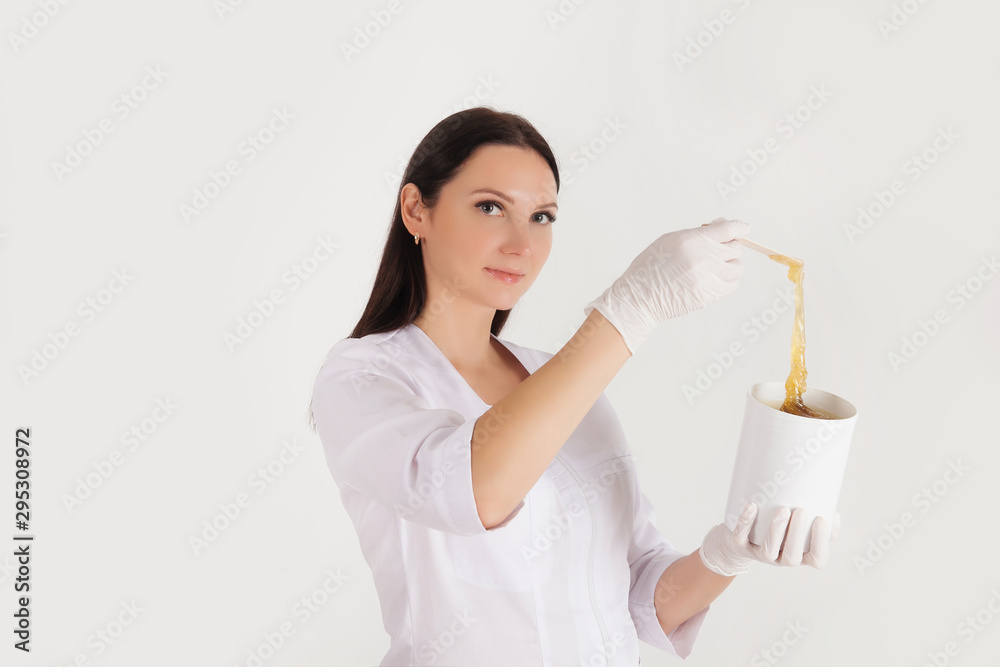 Depilation and hair removal concept. Mockup free space for text. Beautiful female doctor in medical gown uniform with sugar paste Depilation and hair removal concept. Mockup free space for text. Beautiful female doctor in medical gown uniform with sugar paste