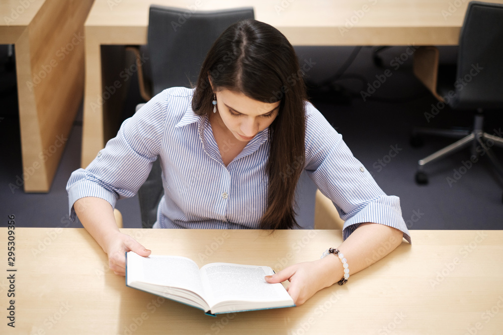 Young woman reading book in public library Young woman reading book in public library