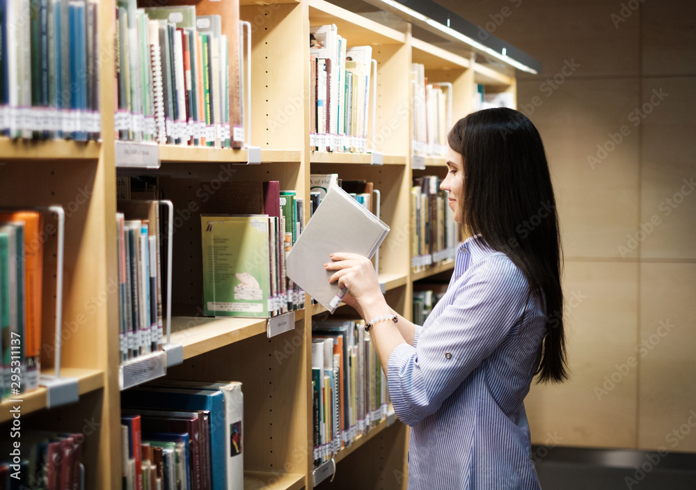 Young woman choosing book in public library Young woman choosing book in public library