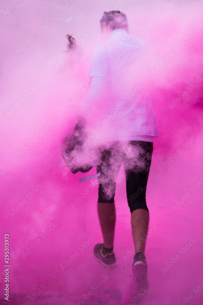 Une personne courant dans de la poudre rose. Une fumée rose de rêve. Holi. Une course de couleurs.