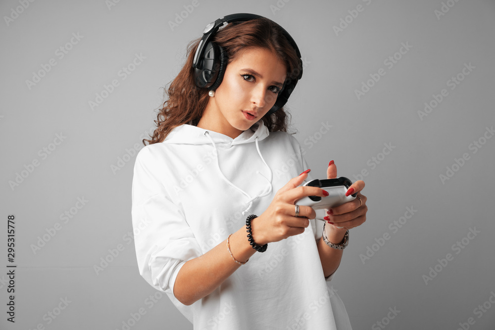 Young pretty woman playing with console joystick over a gray background Young pretty woman playing with console joystick over a gray background