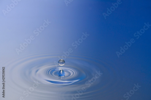 Water drops falling against the water surface splashing the background image