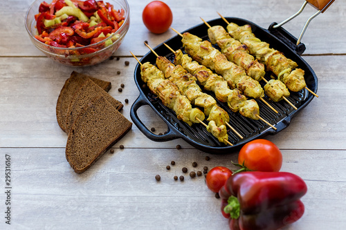 chicken skewers in a pan with pepper salad and tomato and spices