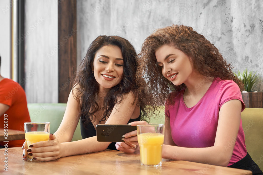 Two girls sitting in cafe, drinking juice and doing selfie Two girls sitting in cafe, drinking juice and doing selfie