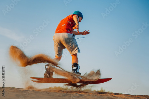 Photography Tourist Sandboarding In the Desert Man jumps in and does the trick