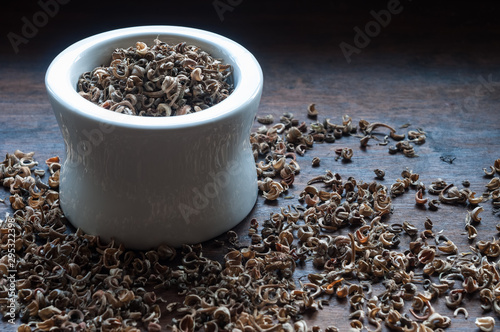 marigold seeds in a white bowl, close-up on a wooden background