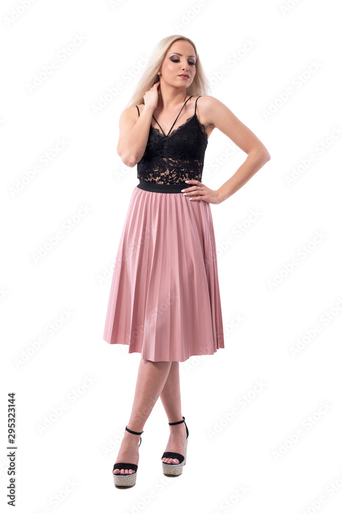 Blonde beauty woman fashion model in skirt and lace top posing with hand on neck looking down. Full body isolated on white background. 