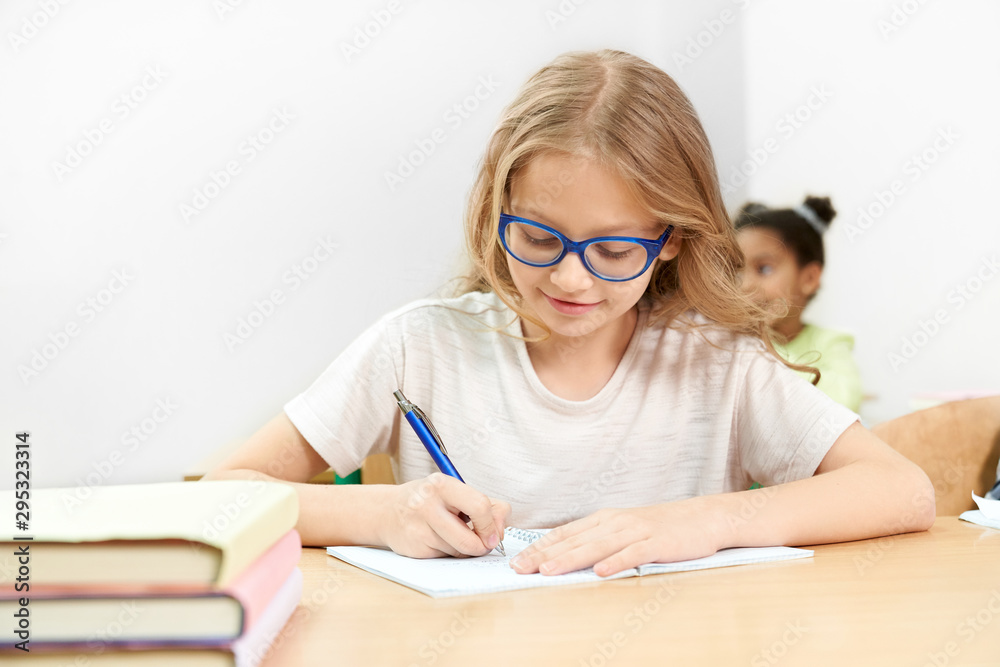 Front view of studious girl doing task on lesson in school Front view of studious girl doing task on lesson in school