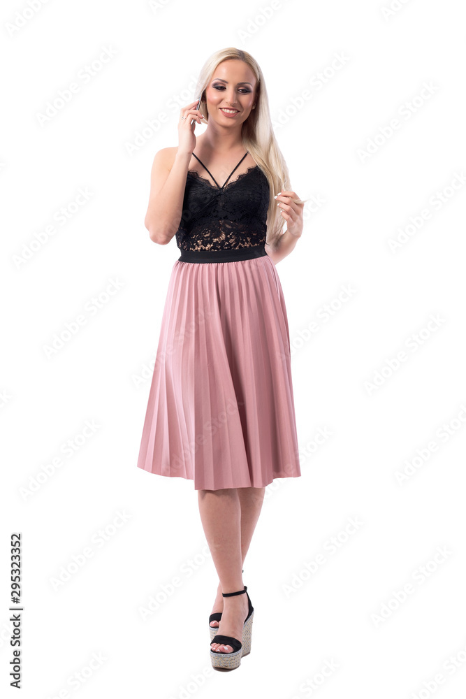 Young happy woman in elegant style fashion walking and talking on cellphone looking down. Full body isolated on white background. Young happy woman in elegant style fashion walking and talking on cellphone looking down. Full body isolated on white background.