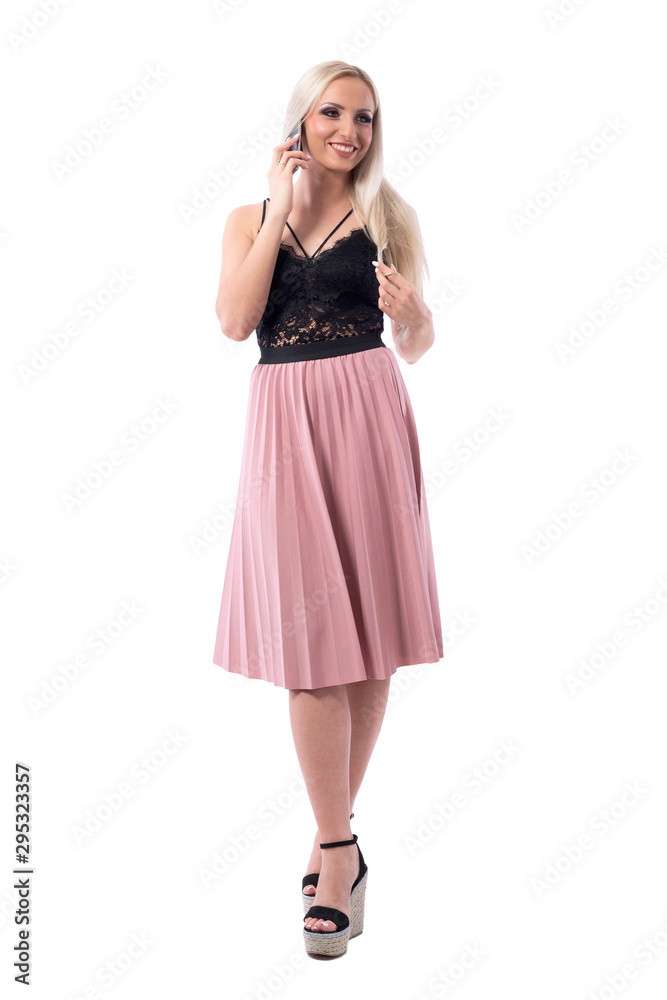 Happy confident young well dressed stylish woman walking and talking on the phone looking away. Full body isolated on white background. 