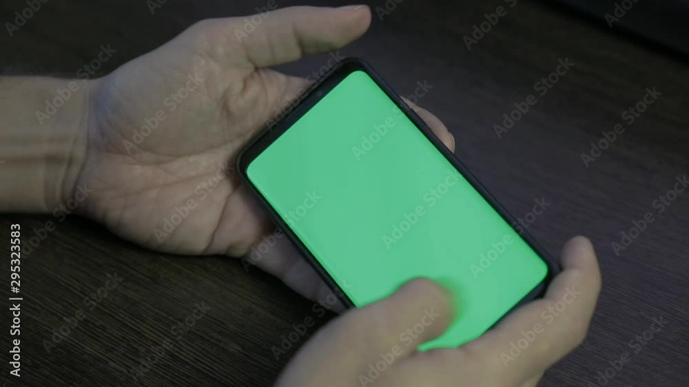 using smart phone with green screen. hands scrolling pages, tapping on touch screen. top view. Chroma key. using smart phone with green screen. hands scrolling pages, tapping on touch screen. top view. Chroma key.