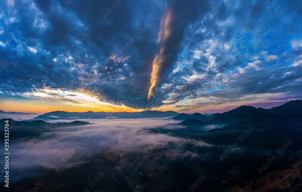 Aerial view amazing sunrise over of the Carpathian Mountains or Carpathians with the village under fog.