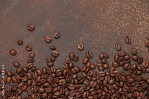 Coffee beans sprinkled on brown background. Flat lay, top view.