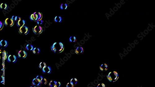 Colorful soap bubbles fly across black background. 