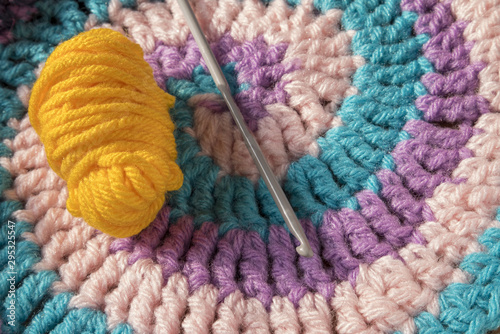 Hand knitted crochet. Needle knitting. Yellow wool ball. Wool, textile background, pink, lilac and light blue colours.