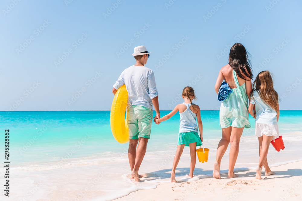 Happy beautiful family of four on white beach