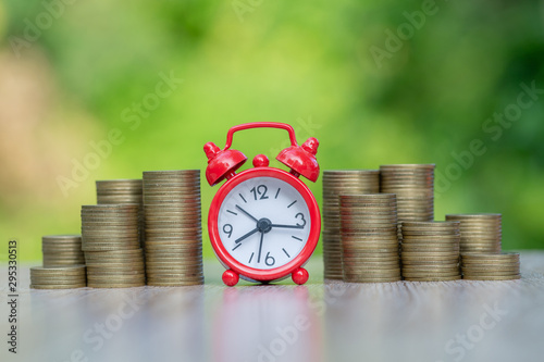 A red alarm clock placed in the middle of a pile of coins left and right. Investment, save money. The time to invest Real Estate and Mortgages. Saving money in the future. Financial concepts.