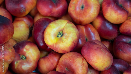 High-angle view of a pile of delicious ripe and juicy Chinese flat peaches of platycarpa variety, also known as Saturn doughnut, doughnut peaches, paraguayo or pan tao peaches at the Farmer's market photo