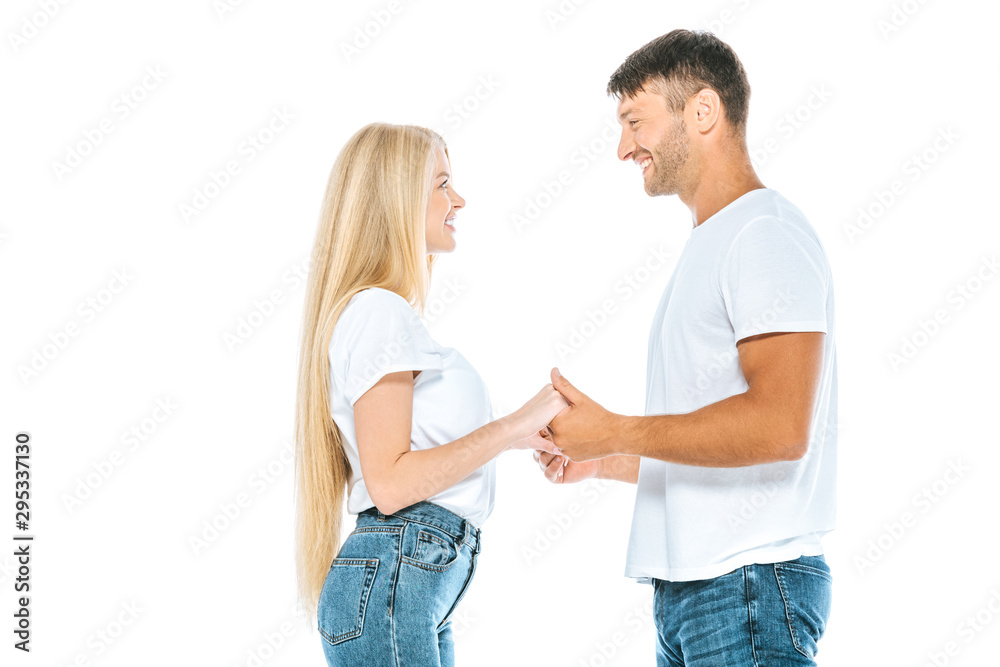 side view of happy couple holding hands while looking at each other isolated on white side view of happy couple holding hands while looking at each other isolated on white