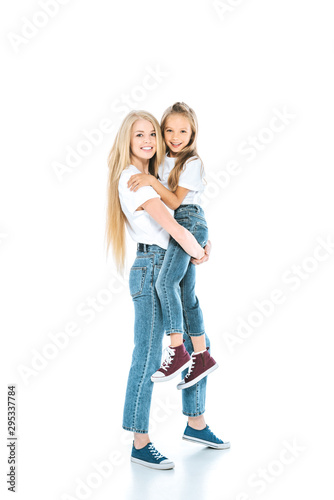 happy mother holding in arms cute daughter and standing on white