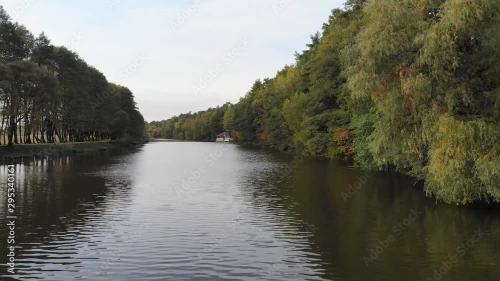 Flight over the forest river. Autumn nature. House by the river.