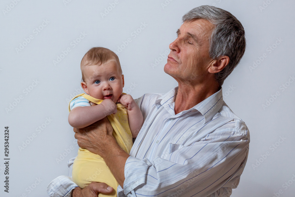 The grandfather and the baby. An old man holding his grandson in his arms The grandfather and the baby. An old man holding his grandson in his arms