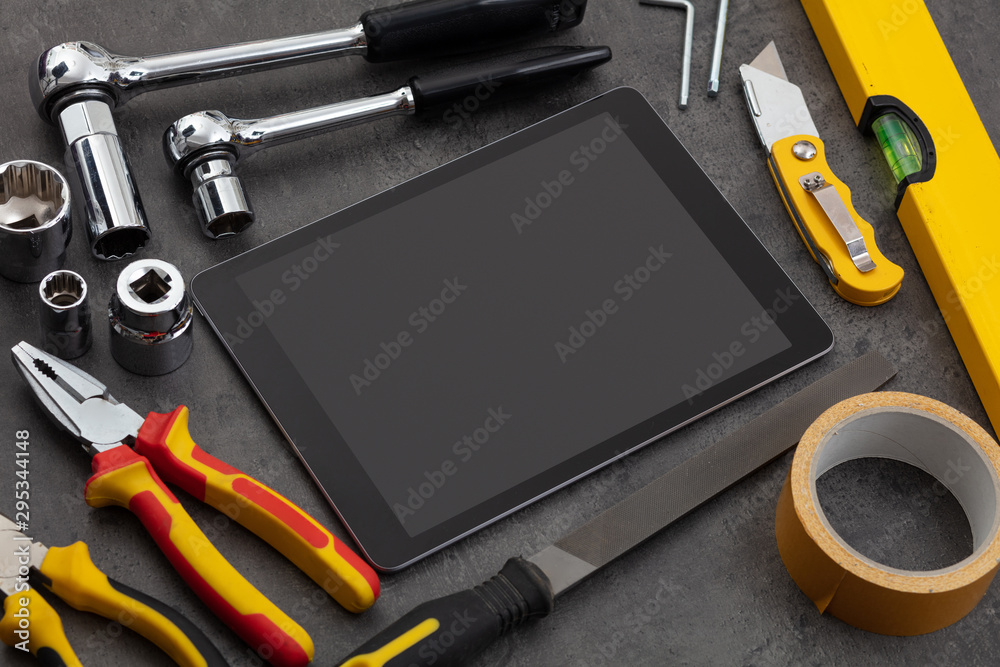 Tablet with empty screen and construction tools around