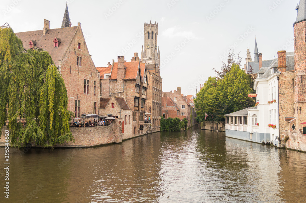 Bruges, Belgium. Medieval ancient houses made of old bricks at water channel with boats in old town. Picturesque landscape.