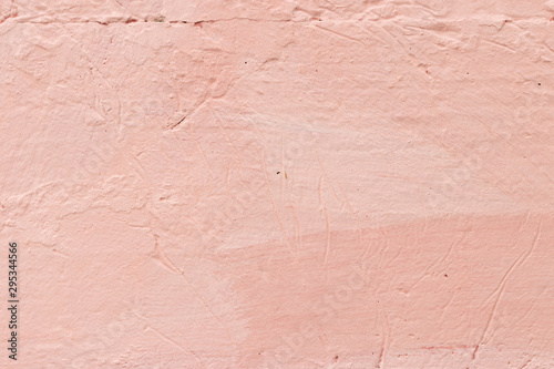 Wall unevenly painted in pink-coral color with scratches and cra