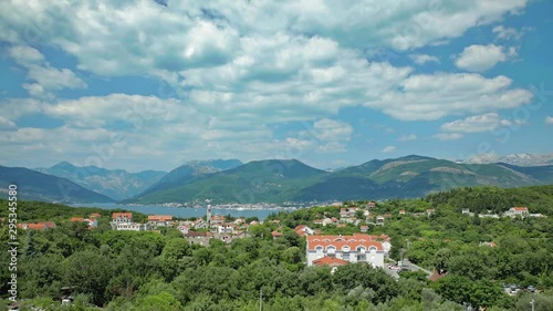 Beautiful timelapse of clouds passing over Montenegro landscape of a village, trees, water and mountains in the summer. photo