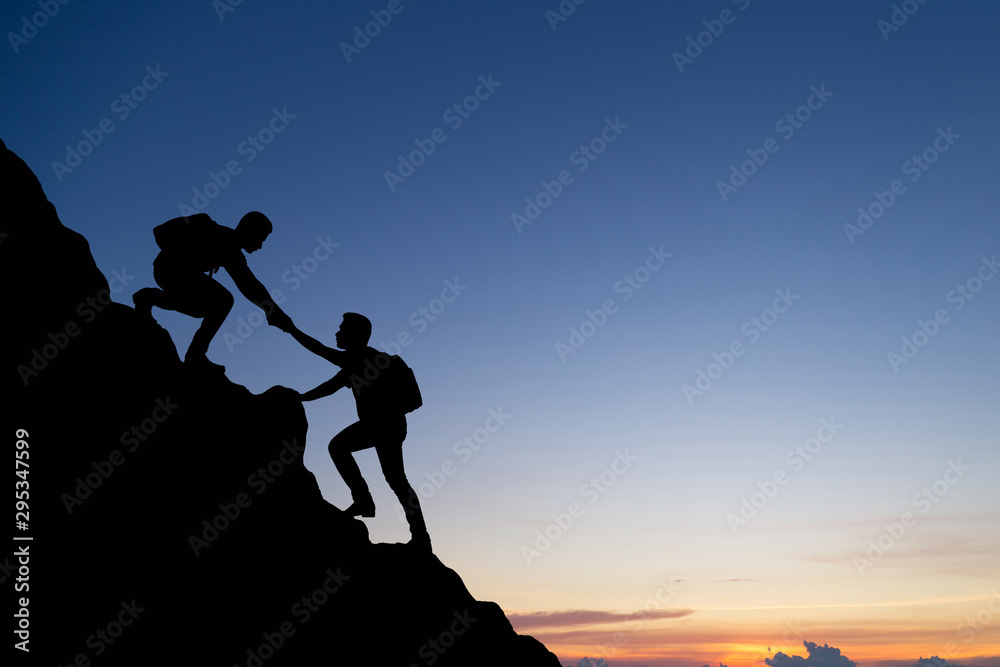 Silhouette of people helping each other hike up a mountain at sunset background. Teamwork, success and goal concept. - obrazy, fototapety, plakaty 