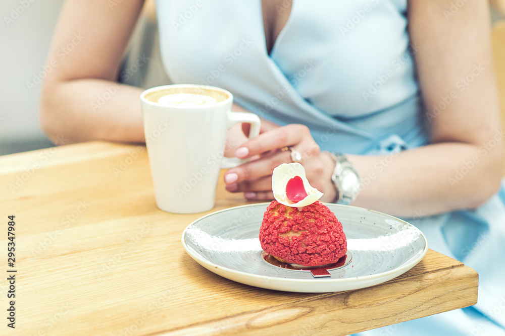 Woman with tasty piece of cake and cup of coffee in cafe close up. Slice of cake on the plate on the wooden table. Woman with tasty piece of cake and cup of coffee in cafe close up. Slice of cake on the plate on the wooden table.