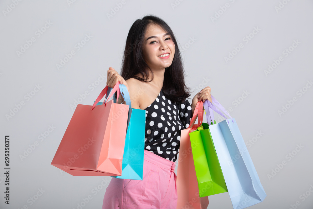 Shopping woman holding bags, isolated on gray studio background Shopping woman holding bags, isolated on gray studio background