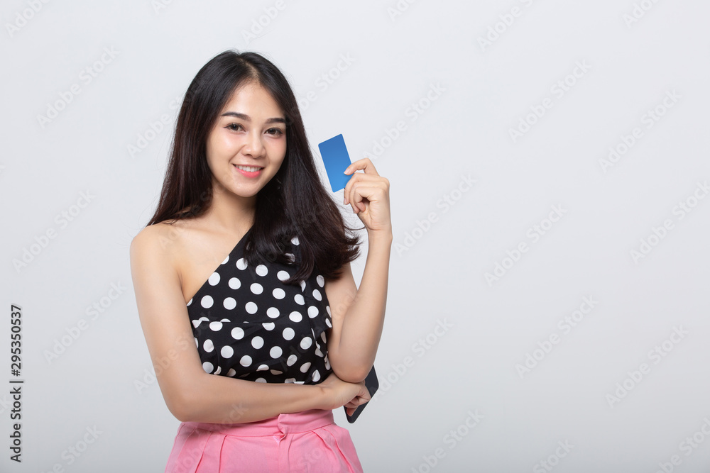 Close-up portrait of young smiling woman holding credit card isolated on gray background Close-up portrait of young smiling woman holding credit card isolated on gray background